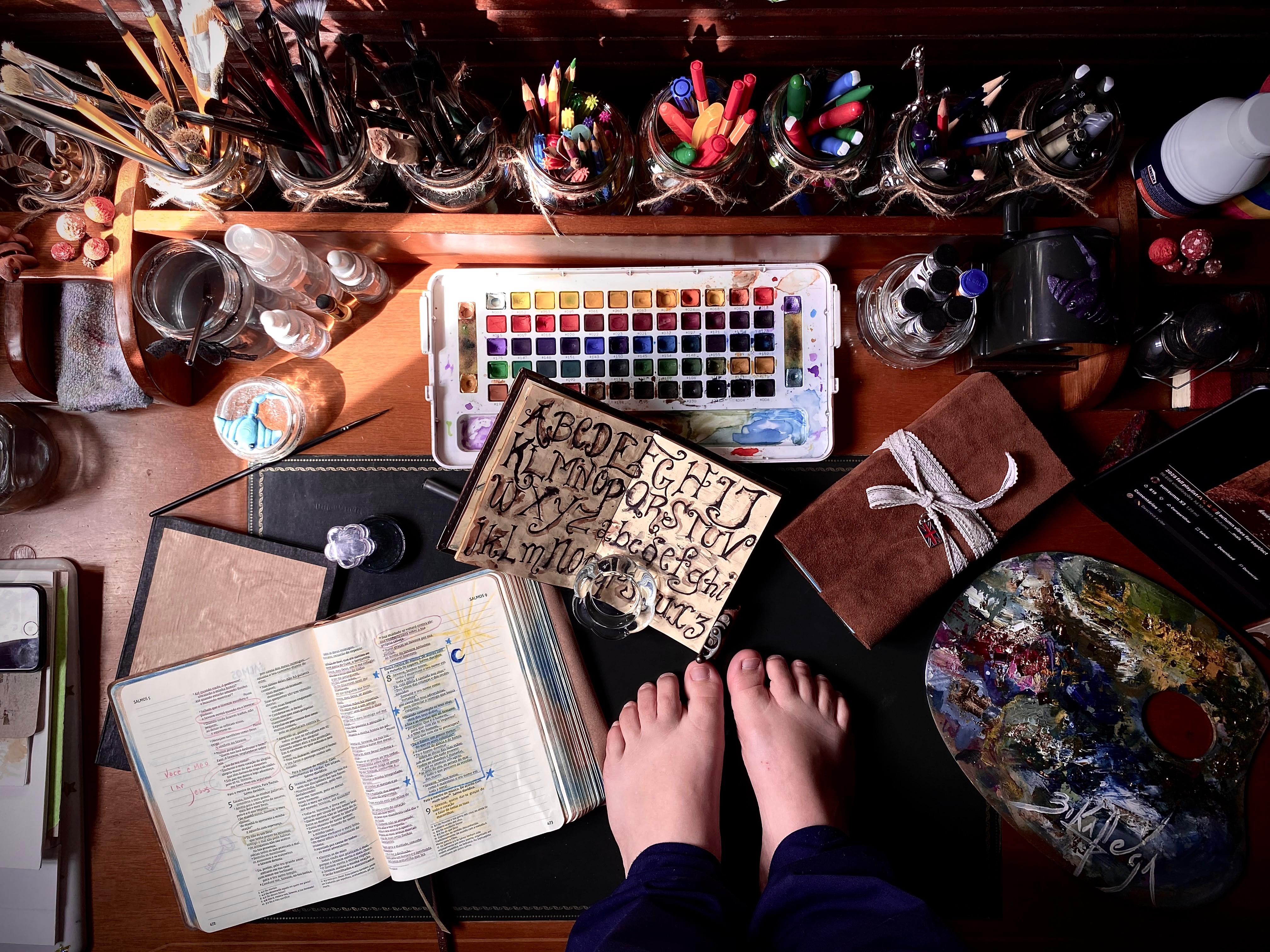 Laboratório criativo de Bianca, com pincéis, tintas, livros e materiais de arte